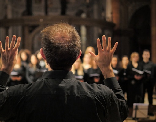 Choir performing in a cathedral led by a musician during a Christmas concert in London.