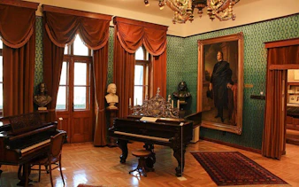 Franz Liszt House Museum interior with pianos and busts in Budapest.