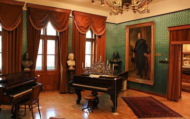 Franz Liszt House Museum interior with pianos and busts in Budapest.
