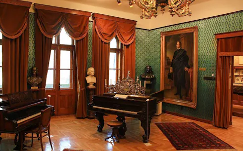 Franz Liszt House Museum interior with pianos and busts in Budapest.