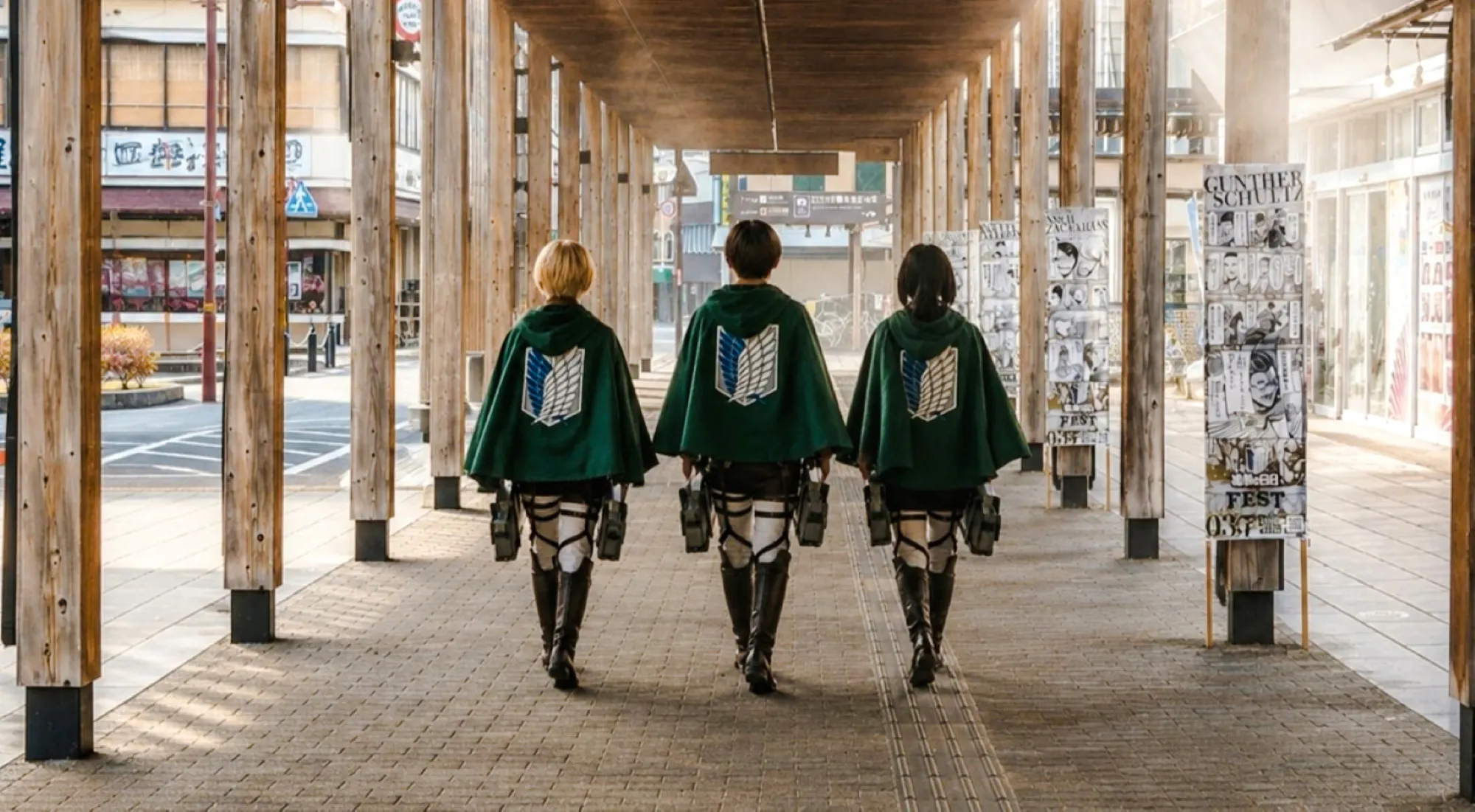 Three people in cosplay walking under wooden beams in Hita, part of the Attack on Titan Pilgrimage Day Tour.