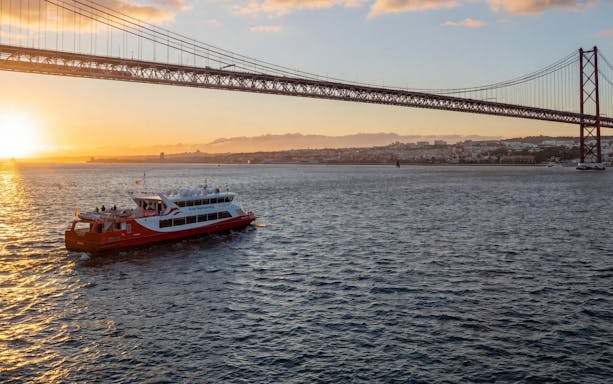Lisbon sunset cruise with DJ and open bar under 25 de Abril Bridge.