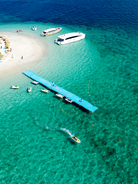 Aerial view of Khai Island beach with boats and pier, Thailand.
