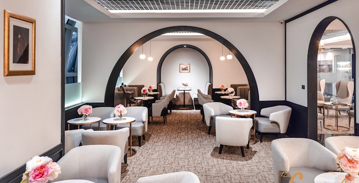 Coral First Class Lounge seating area with tables and flowers, Bangkok airport, Thailand.