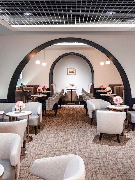 Coral First Class Lounge seating area with tables and flowers, Bangkok airport, Thailand.