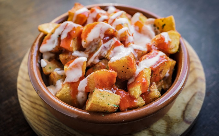Patatas Bravas served in a clay dish on the Tapas Walking Tour in Triana.