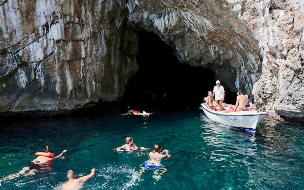 Swimmers and a boat near the entrance of the Blue Cave, Kotor.