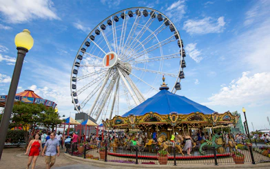 Ferris wheel and carousel at Navy Pier, Chicago, with visitors enjoying the attractions.