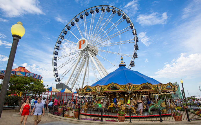 Ferris wheel and carousel at Navy Pier, Chicago, with visitors enjoying the attractions.