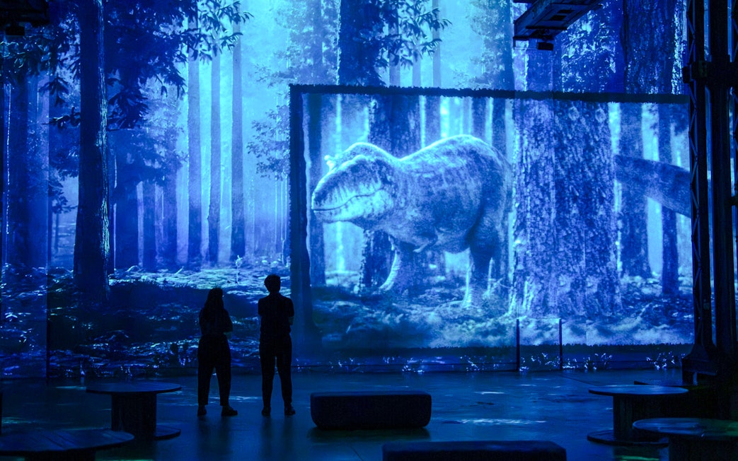 Visitors viewing dinosaur projection at Prehistoric Planet exhibition, Atelier des Lumières, Paris.