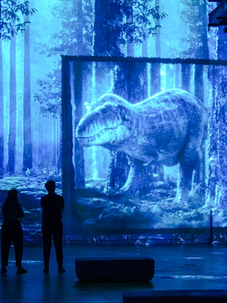 Visitors viewing dinosaur projection at Prehistoric Planet exhibition, Atelier des Lumières, Paris.