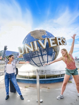 Guests posing in front of the Universal globe and fountain at Universal Studios Orlando.