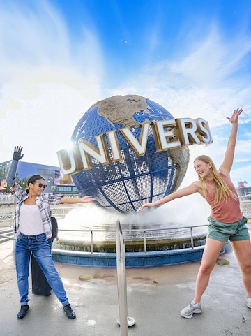 Guests posing in front of the Universal globe and fountain at Universal Studios Orlando.