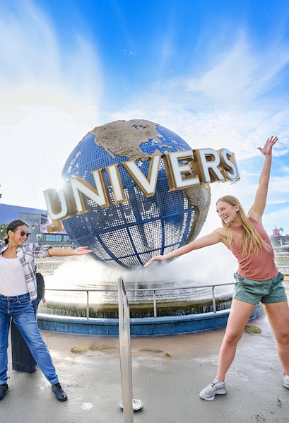 Guests posing in front of the Universal globe and fountain at Universal Studios Orlando.