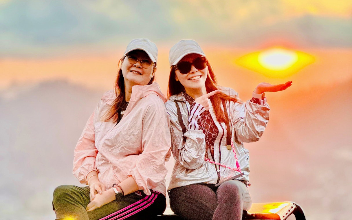 Friends sitting on a jeep at sunrise near Mount Batur, Bali.