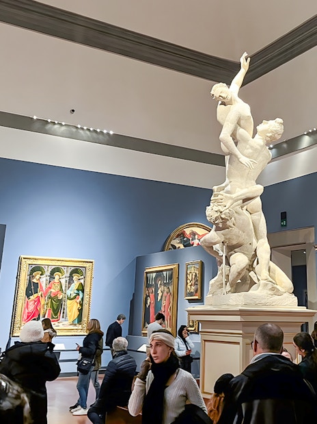 Sculpture of the Rape of Sabine Women at Accademia Gallery, Florence, surrounded by visitors.