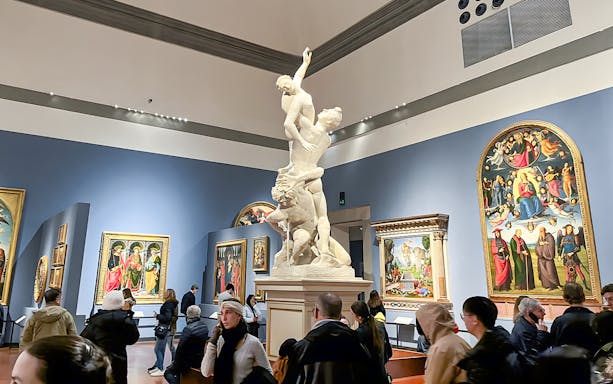Sculpture of the Rape of Sabine Women at Accademia Gallery, Florence, surrounded by visitors.