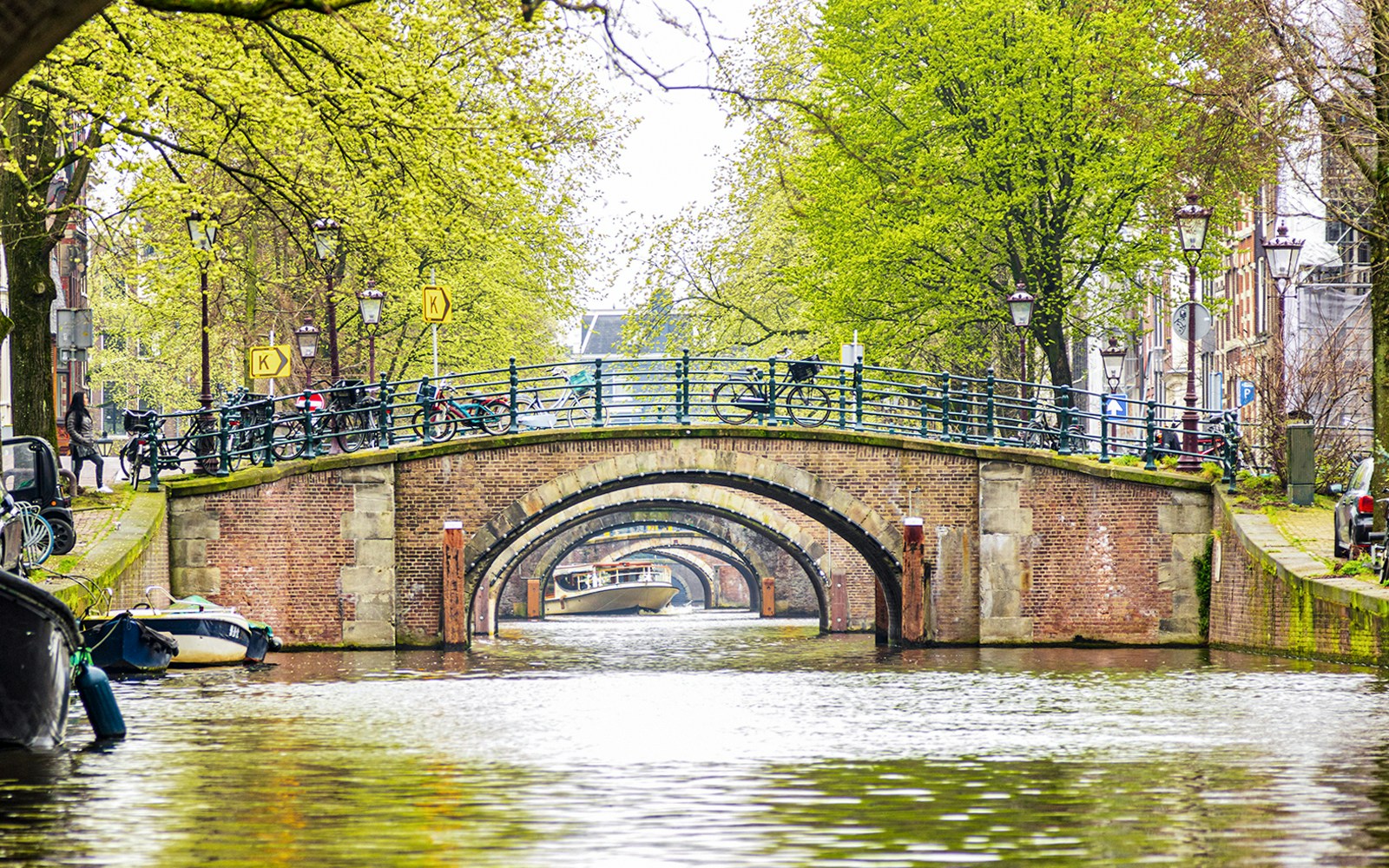 Canal view of seven bridges in Amsterdam with bicycles and trees lining the path.