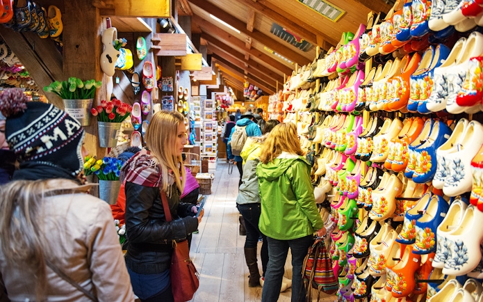 Visitors browsing colorful wooden clogs at a shop in Zaanse Schans, Netherlands.
