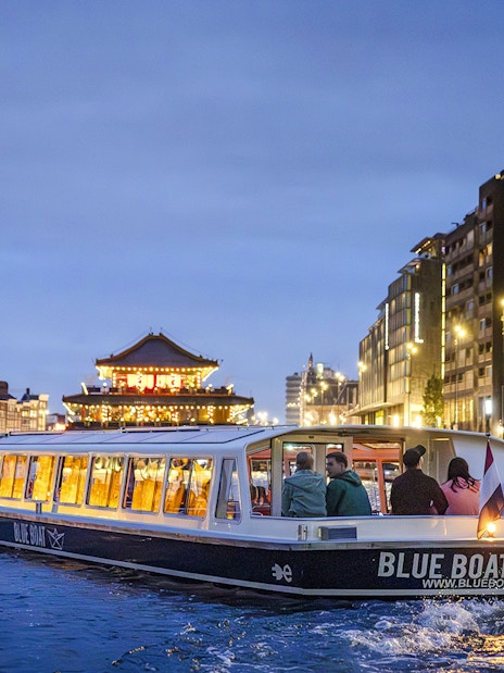 Winter evening canal cruise in Amsterdam with city lights and historic buildings.