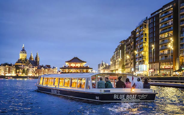 Winter evening canal cruise in Amsterdam with city lights and historic buildings.