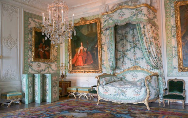 Royal apartment interior with ornate bed and paintings, Versailles Palace.