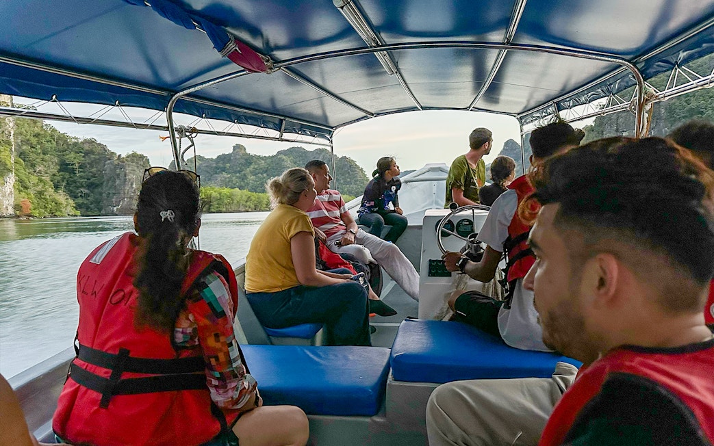 Passengers on a covered tour boat viewing karst landscape during Langkawi mangrove tour.