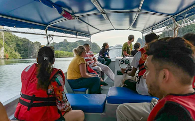 Passengers on a covered tour boat viewing karst landscape during Langkawi mangrove tour.