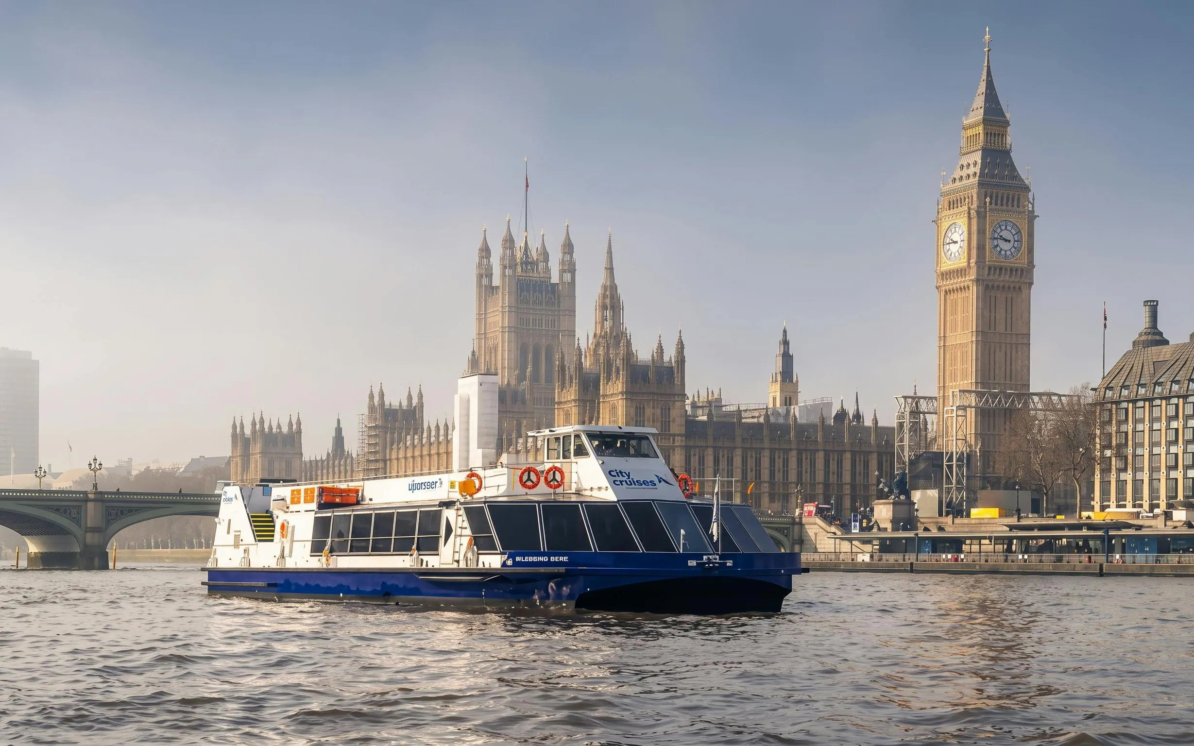 City cruise boat on the Thames with Big Ben and Houses of Parliament in London.
