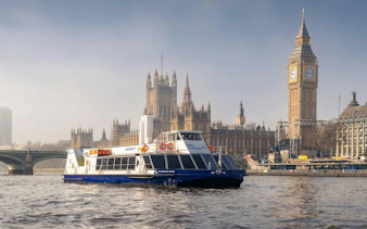 City cruise boat on the Thames with Big Ben and Houses of Parliament in London.