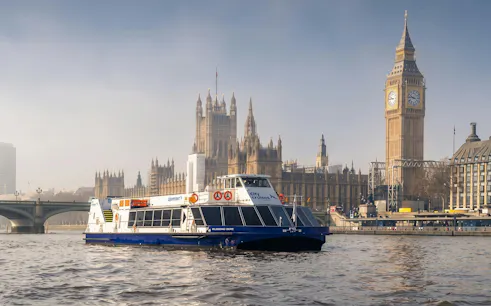 City cruise boat on the Thames with Big Ben and Houses of Parliament in London.