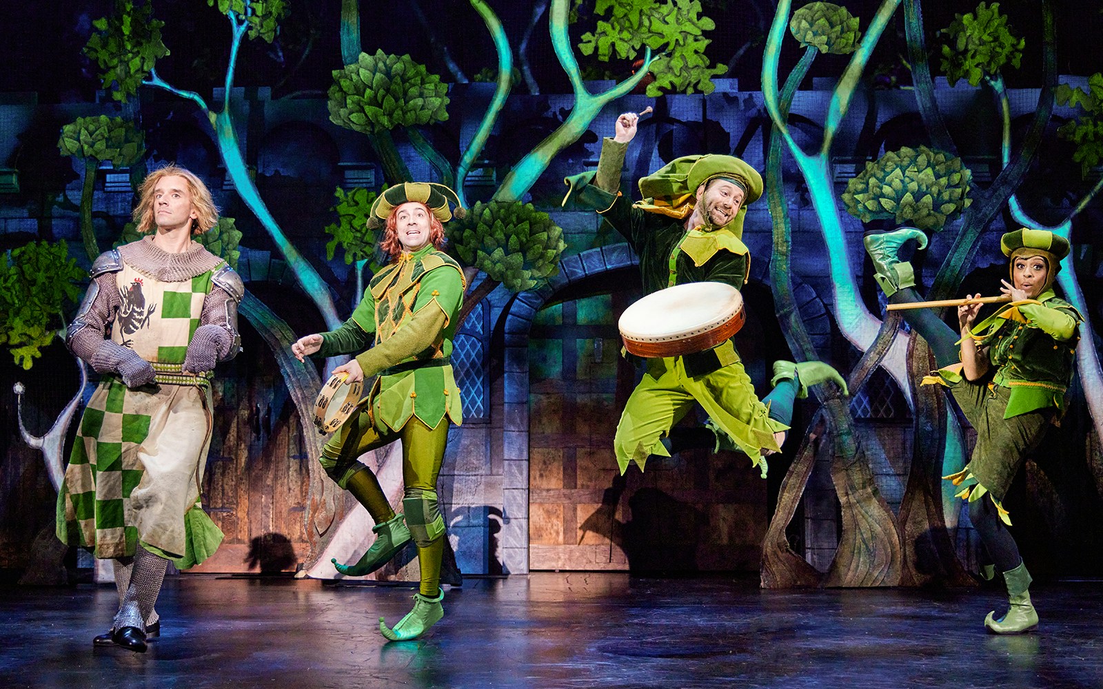 Performers in medieval costumes on stage during a Spamalot musical scene.
