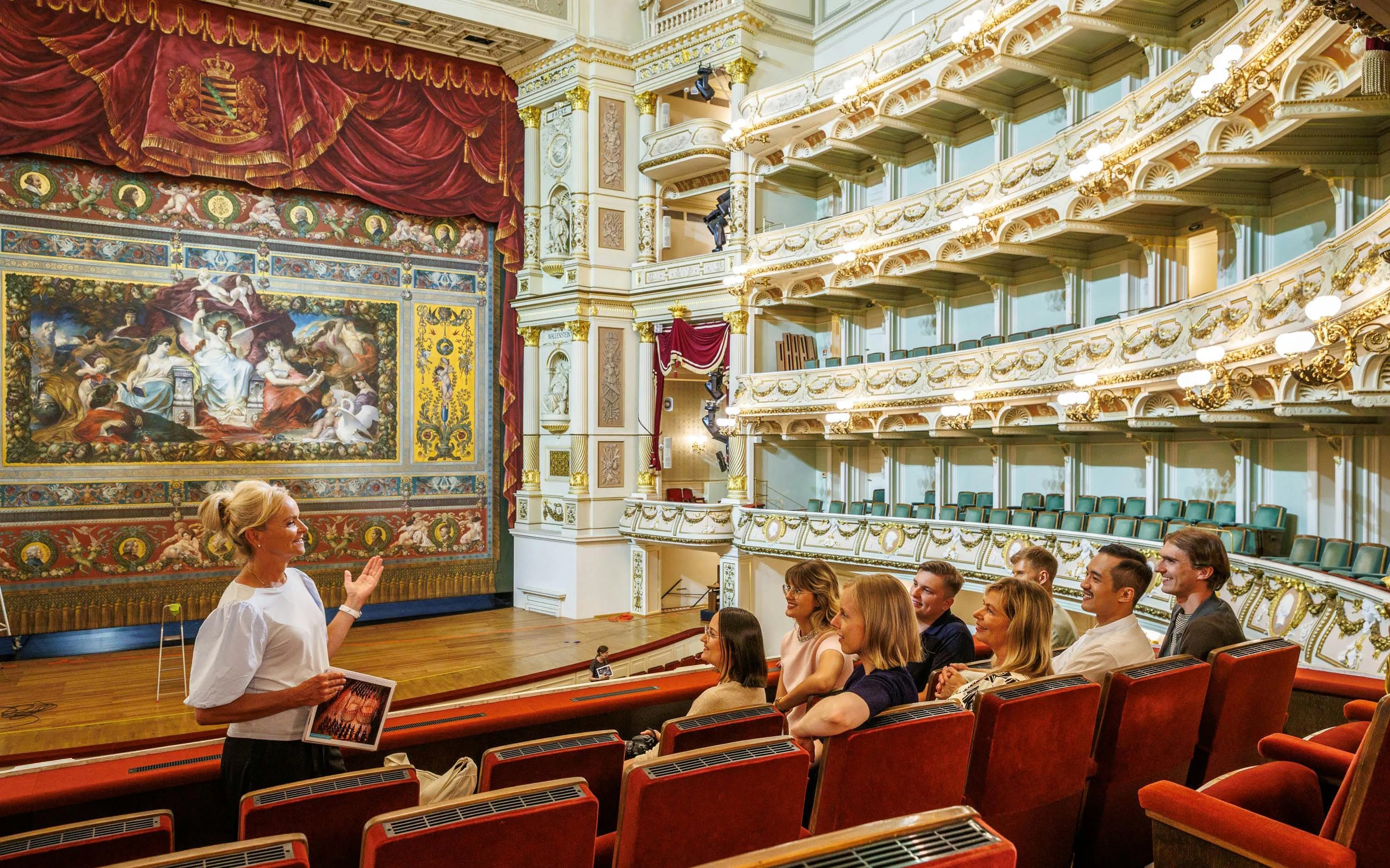 Tour guide explaining the interior of Semper Opera House to visitors.