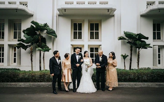 Wedding party posing outside a white building in Jakarta during a professional photoshoot by Viufinder.