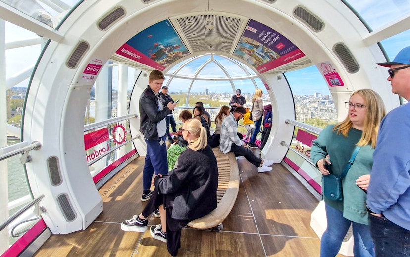 Visitors inside a London Eye capsule with city views in the background.