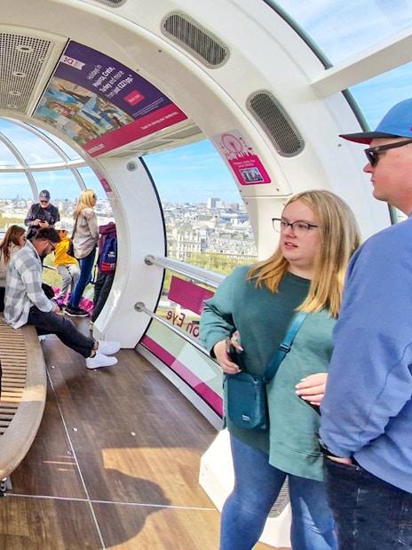 Visitors inside a London Eye capsule with city views in the background.