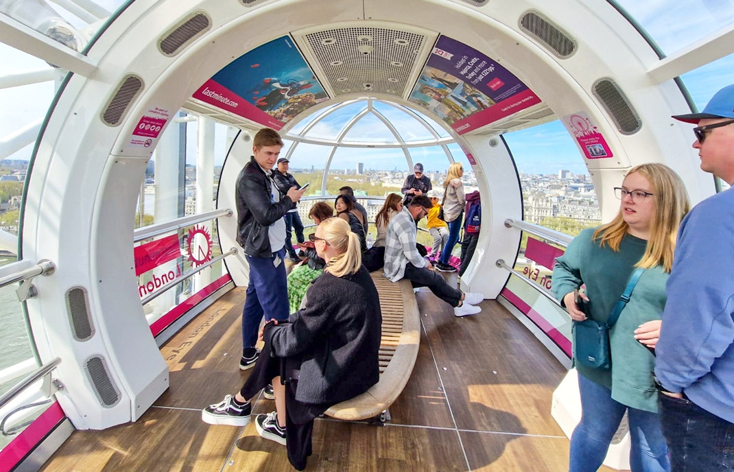 Visitors inside a London Eye capsule with city views in the background.
