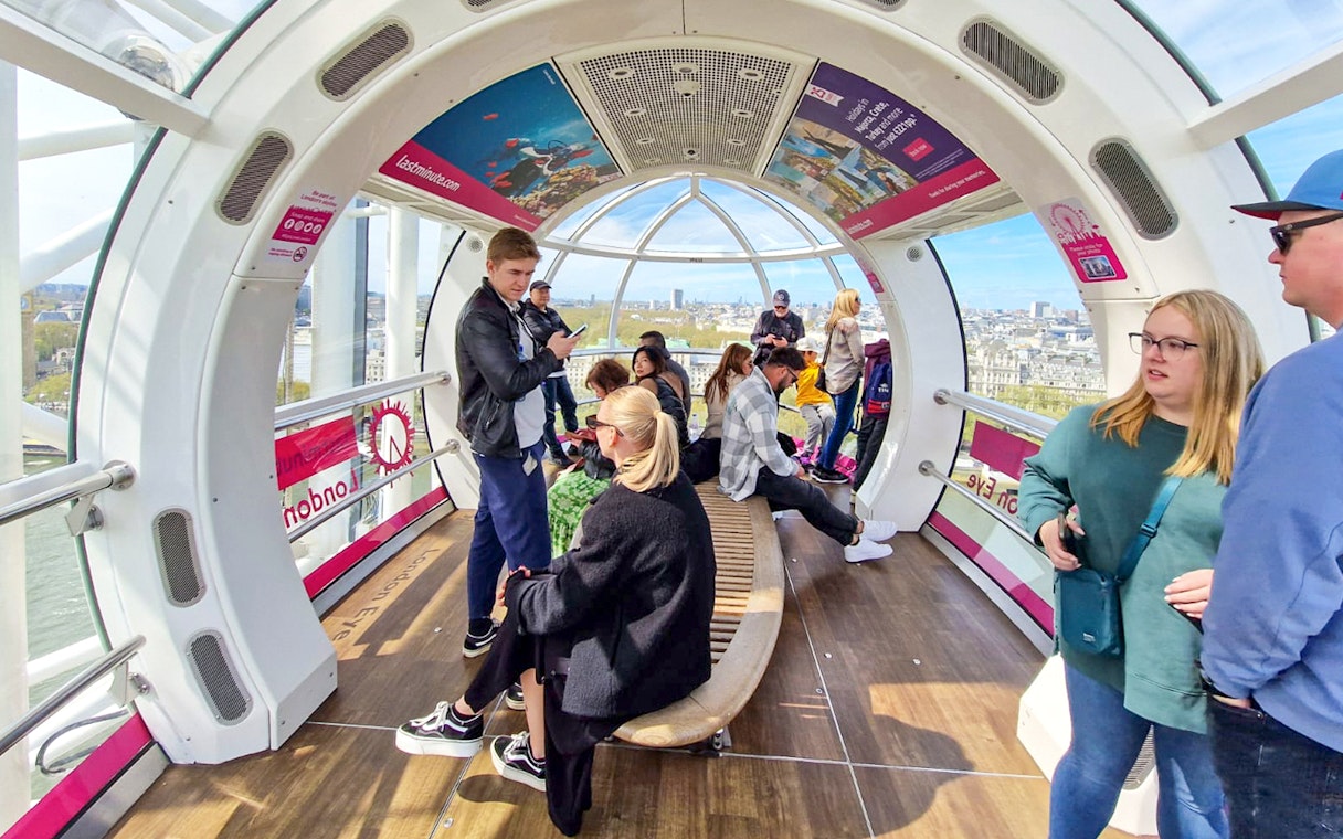 Visitors inside a London Eye capsule with city views in the background.