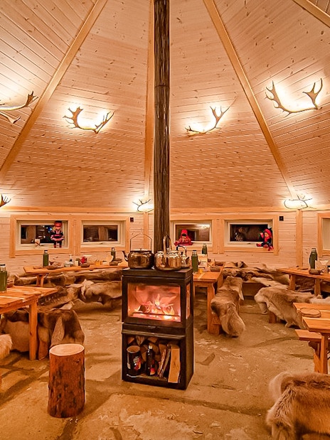 Cozy wooden cabin interior with fireplace, Tromso reindeer sledding tour.