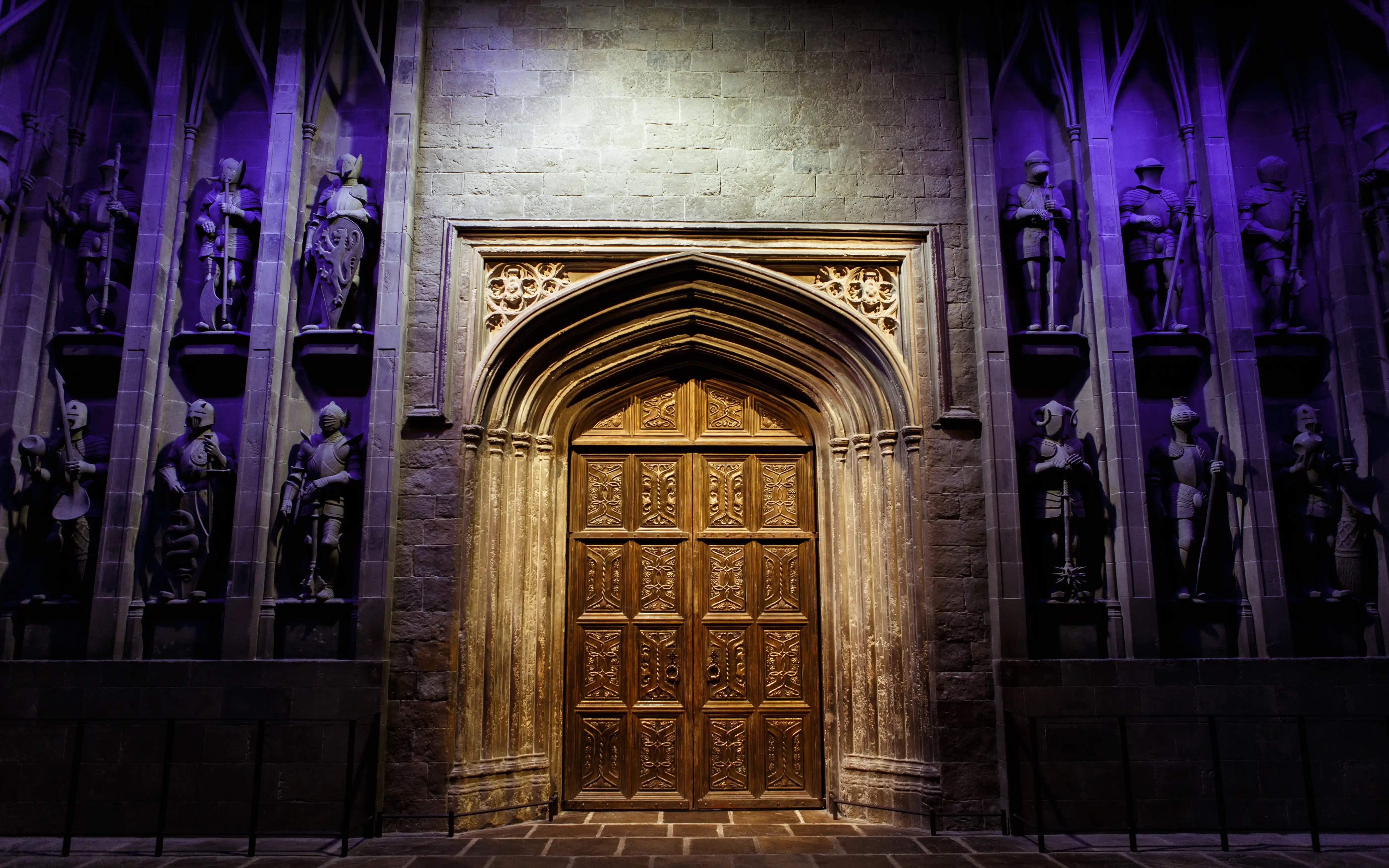 Great Hall entrance at Harry Potter™ Warner Bros. Studio Tour, featuring ornate wooden doors and knight statues.