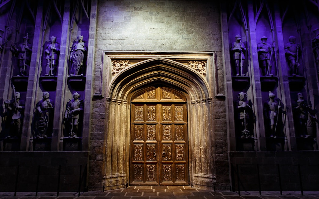 Great Hall entrance at Harry Potter™ Warner Bros. Studio Tour, featuring ornate wooden doors and knight statues.