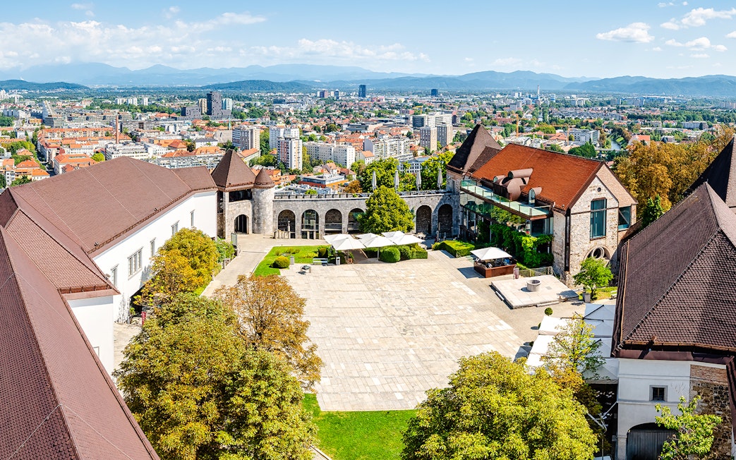 Aerial view of Ljubljana Castle courtyard with cityscape in the background.
