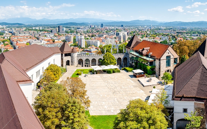 Aerial view of Ljubljana Castle courtyard with cityscape in the background.