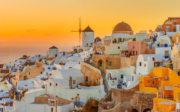 Oia village with whitewashed buildings and windmill at sunset, Santorini, Greece.