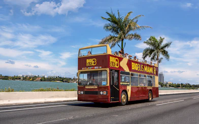 Miami double-decker bus tour along waterfront with palm trees and city skyline.