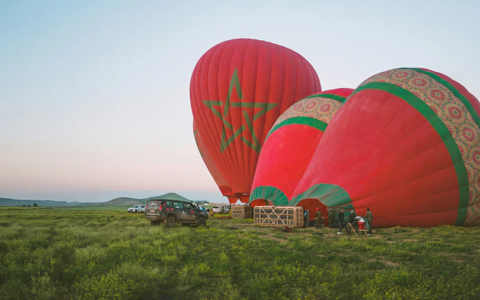 Hot air balloons preparing for sunrise flight in Marrakesh field.