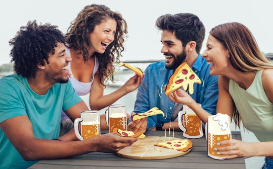 Friends enjoying pizza and beer outdoors, ideal for culinary explorers.