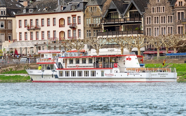 River cruise ship Moselprinz docked by historic buildings in a European town.