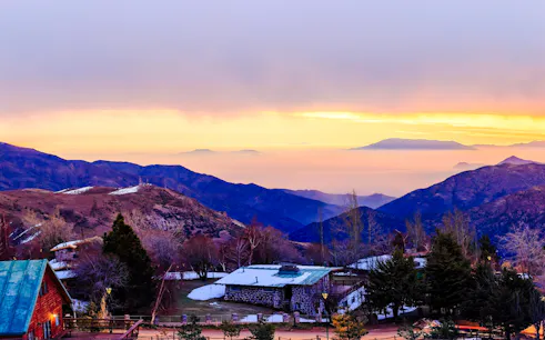 Sunset over the Andes Mountains near Santiago with rustic cabins in the foreground.