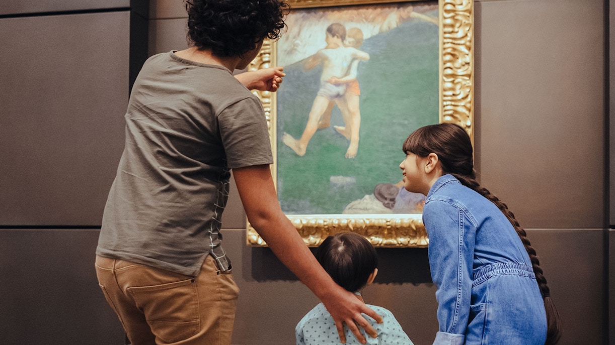 Visitors admiring a painting at Louvre Museum Abu Dhabi exhibit.
